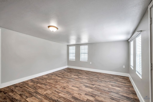 14038 W County Rd 123, Odessa, TX 79765 - empty room with plenty of natural light, dark wood-type flooring, and a textured ceiling