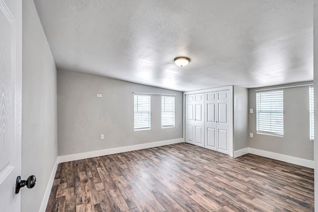 14038 W County Rd 123, Odessa, TX 79765 - unfurnished bedroom with wood finished floors, multiple windows, a textured ceiling, and a closet