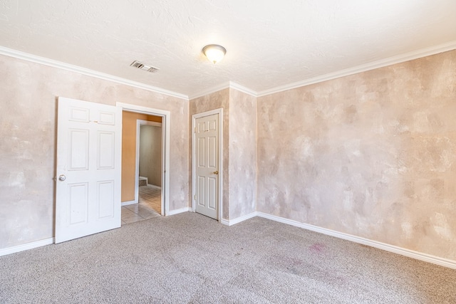 spare room featuring carpet flooring, visible vents, baseboards, and ornamental molding
