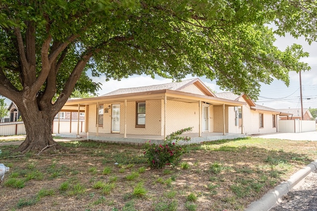 view of front of house with brick siding, covered porch, and fence