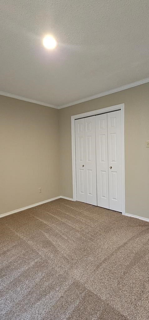 2304 Regal Pl, Midland, TX 79707 - unfurnished bedroom featuring crown molding, baseboards, carpet, a textured ceiling, and a closet