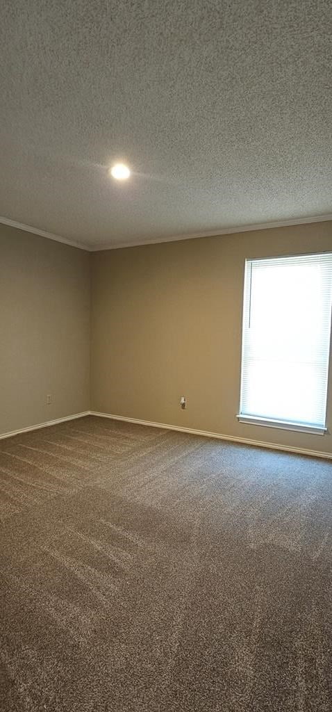 2304 Regal Pl, Midland, TX 79707 - spare room featuring dark carpet, a textured ceiling, and baseboards