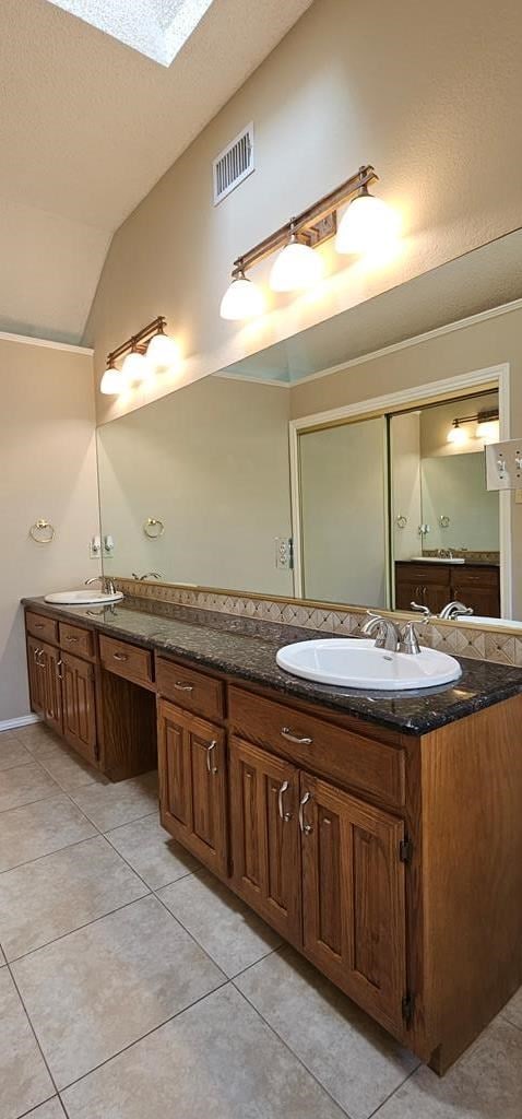 2304 Regal Pl, Midland, TX 79707 - full bath with double vanity, a skylight, lofted ceiling, and tile patterned floors