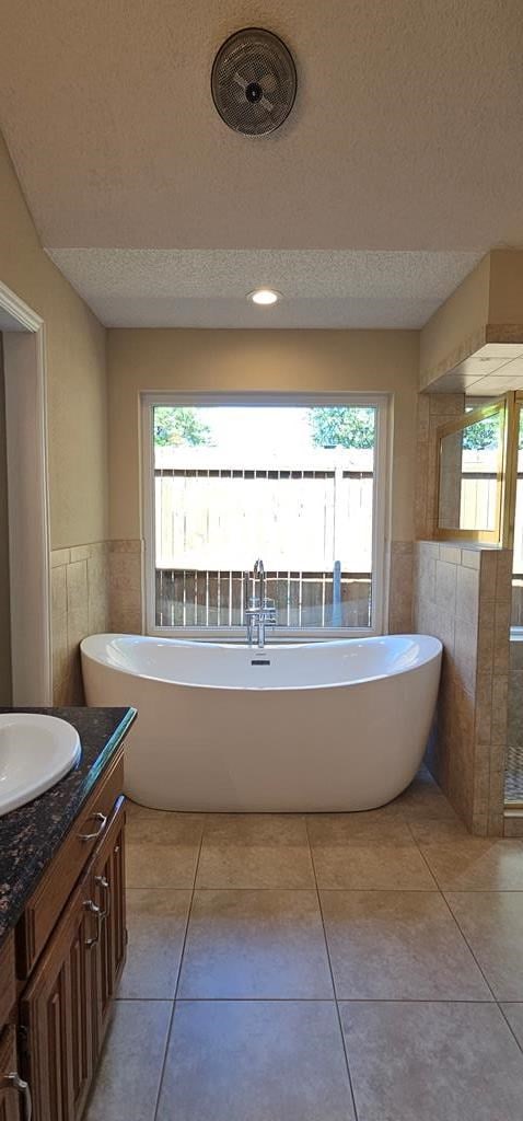 2304 Regal Pl, Midland, TX 79707 - bathroom with a textured ceiling, tile walls, plenty of natural light, vanity, and wainscoting