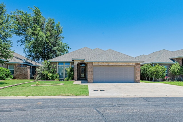 104 Waimea Dr, Odessa, TX 79762 - french provincial home with driveway, an attached garage, a front yard, brick siding, and a shingled roof