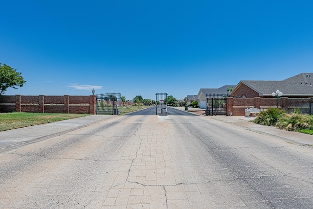 104 Waimea Dr, Odessa, TX 79762 - view of asphalt road with a gate and sidewalks