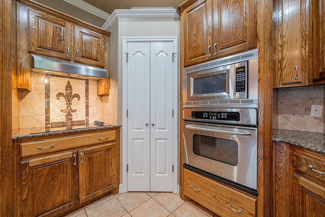 104 Waimea Dr, Odessa, TX 79762 - kitchen with appliances with stainless steel finishes, light tile patterned floors, decorative backsplash, dark stone countertops, and ornamental molding