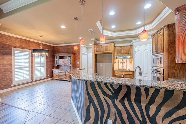 104 Waimea Dr, Odessa, TX 79762 - kitchen featuring stainless steel appliances, stone countertops, brown cabinetry, a chandelier, and crown molding