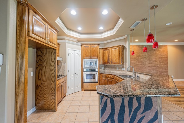 104 Waimea Dr, Odessa, TX 79762 - kitchen featuring appliances with stainless steel finishes, a peninsula, crown molding, tasteful backsplash, and brown cabinetry