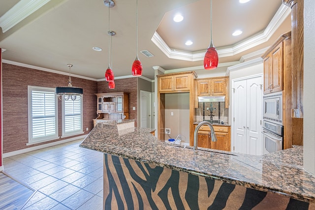 104 Waimea Dr, Odessa, TX 79762 - kitchen with appliances with stainless steel finishes, ornamental molding, dark stone counters, under cabinet range hood, and hanging light fixtures