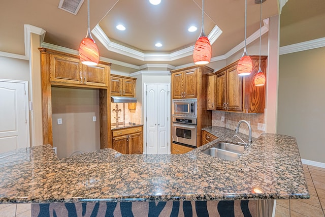104 Waimea Dr, Odessa, TX 79762 - kitchen featuring appliances with stainless steel finishes, brown cabinetry, a peninsula, light tile patterned floors, and backsplash