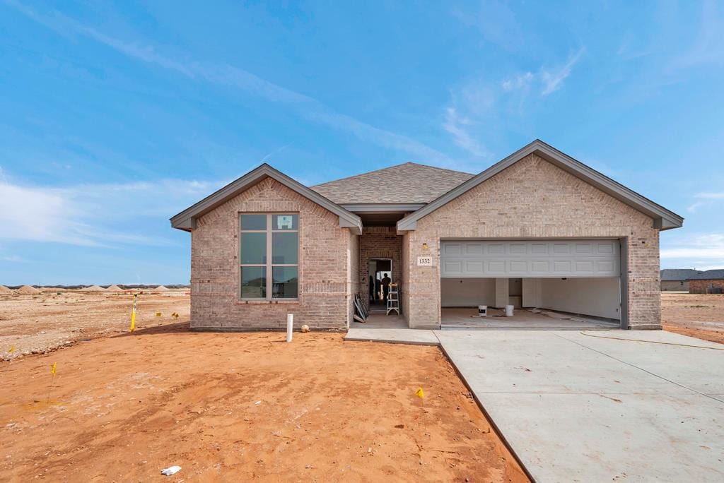 1332 Loess St, Midland, TX 79705 - view of front facade with a garage, brick siding, concrete driveway, and roof with shingles