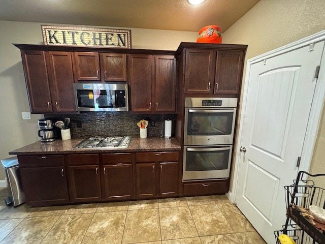 6111 Sun Tea Way, Midland, TX 79705 - kitchen with stainless steel appliances, backsplash, dark brown cabinets, dark stone counters, and light tile patterned floors