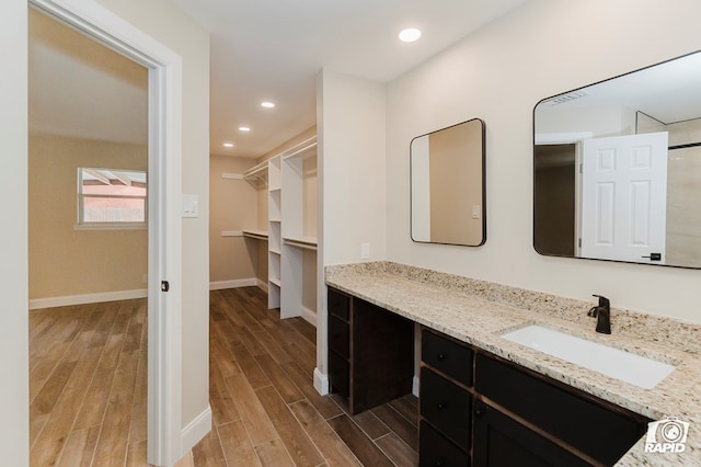 3201 Reo Dr, Midland, TX 79705 - full bathroom featuring wood finished floors, vanity, a walk in closet, and recessed lighting
