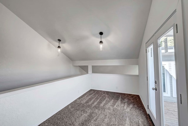 interior space featuring lofted ceiling, dark carpet, and baseboards