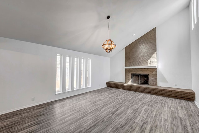 unfurnished living room featuring a fireplace, high vaulted ceiling, wood finished floors, a chandelier, and baseboards