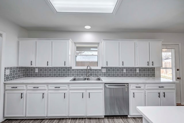 kitchen featuring light countertops, a sink, stainless steel dishwasher, and white cabinetry