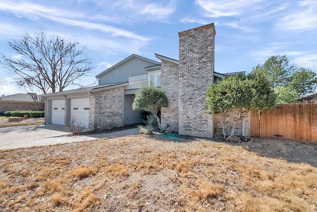 view of front of home with an attached garage, brick siding, fence, driveway, and a chimney