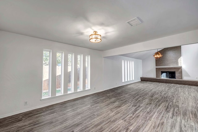 unfurnished living room with visible vents, a fireplace, baseboards, and wood finished floors