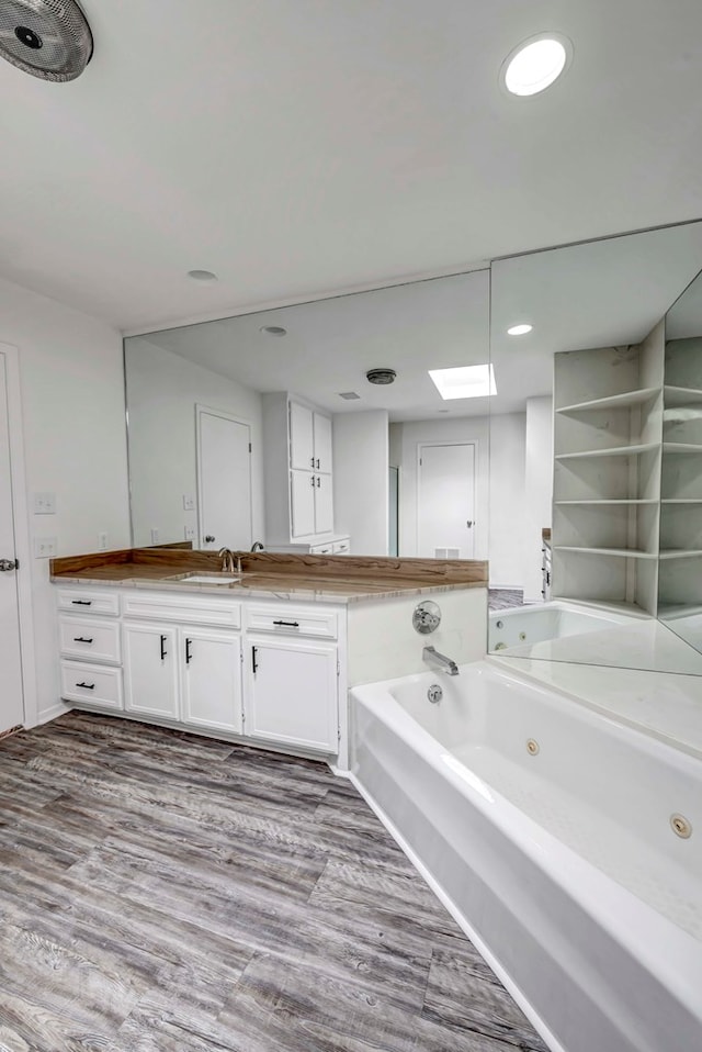 bathroom featuring a tub with jets, wood finished floors, and vanity