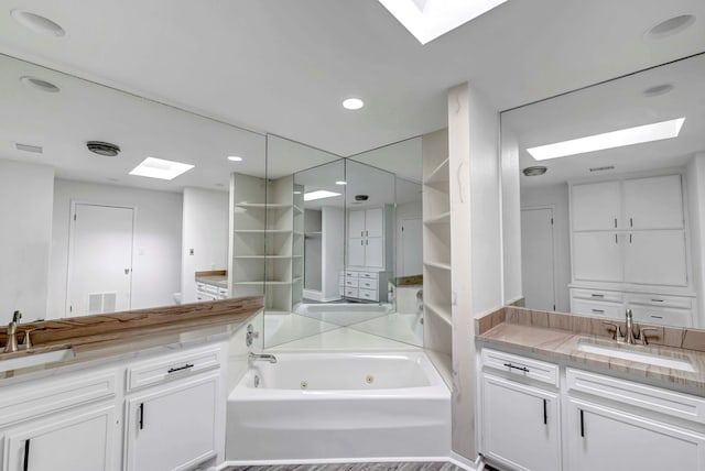 bathroom featuring visible vents, a tub with jets, a closet, and vanity