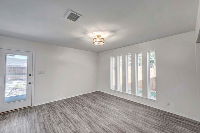 spare room featuring visible vents, a textured ceiling, baseboards, and wood finished floors