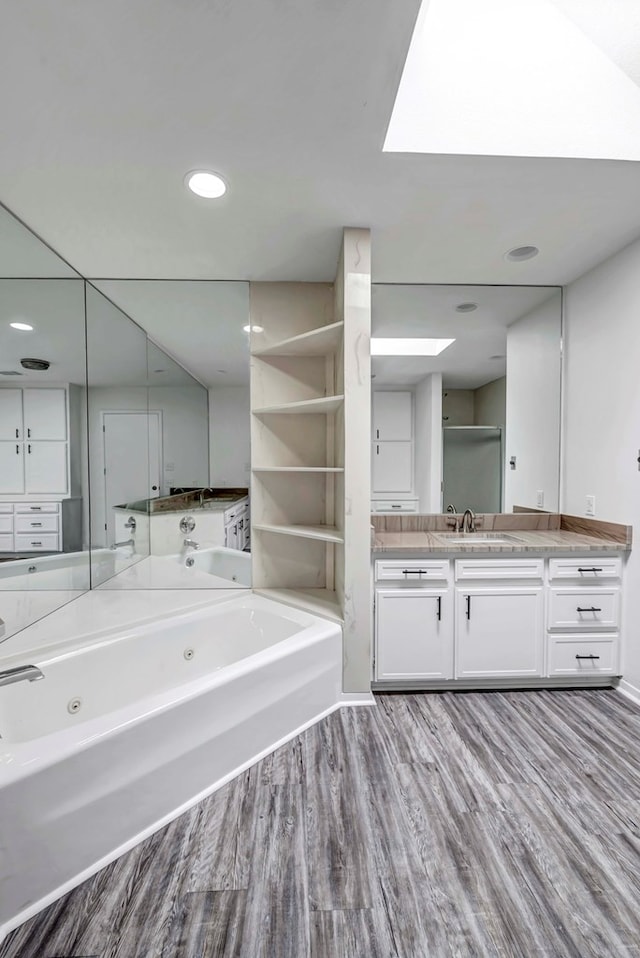 full bathroom with a whirlpool tub, wood finished floors, vanity, and recessed lighting