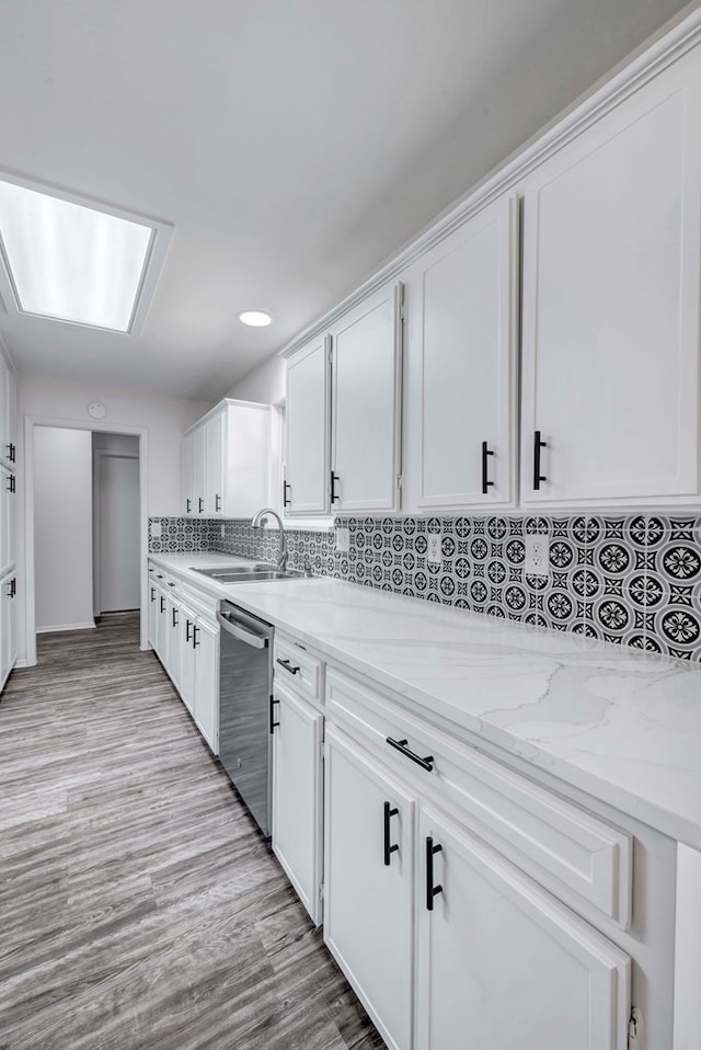 kitchen with a sink, light stone countertops, white cabinetry, and dishwasher