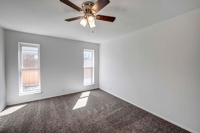 carpeted spare room featuring a ceiling fan, a wealth of natural light, and baseboards