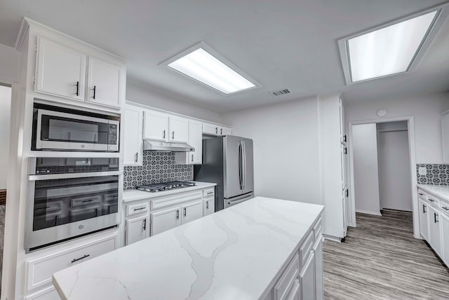 kitchen with stainless steel appliances, white cabinetry, and under cabinet range hood