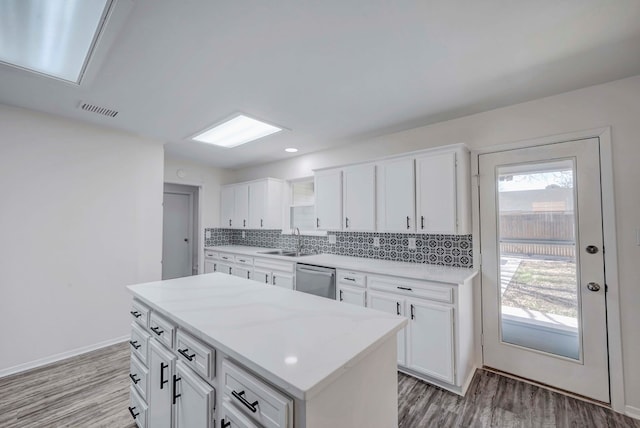 kitchen with a kitchen island, white cabinetry, a sink, and dishwasher