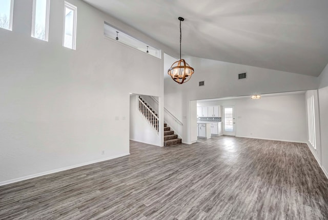 unfurnished living room with a chandelier, high vaulted ceiling, dark wood-type flooring, baseboards, and stairway