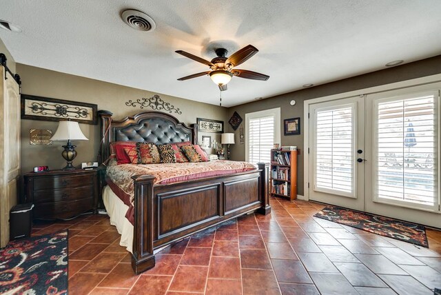 2919 Kirkwood Dr, Odessa, TX 79762 - bedroom with access to outside, dark tile patterned flooring, a barn door, ceiling fan, and a textured ceiling
