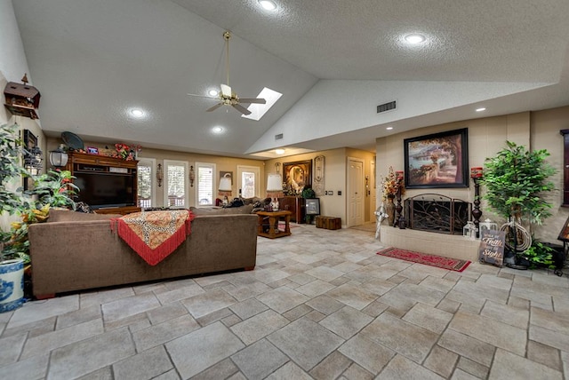 2919 Kirkwood Dr, Odessa, TX 79762 - living room featuring lofted ceiling, a ceiling fan, a textured ceiling, a fireplace with raised hearth, and stone tile floors