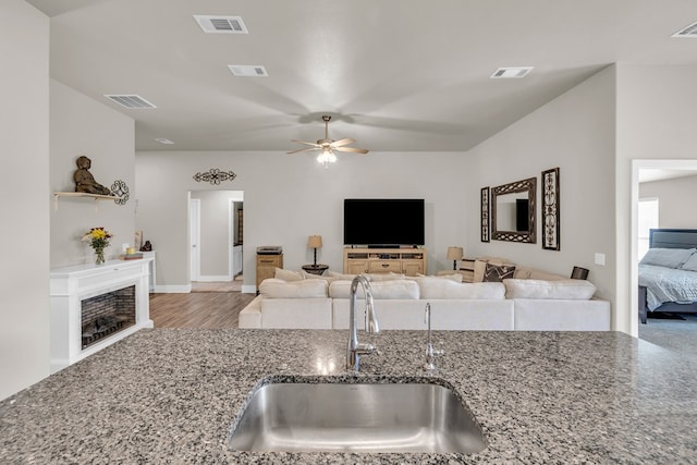 kitchen with stone countertops, ceiling fan, visible vents, and a sink