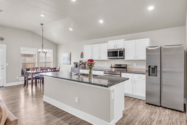 kitchen with light wood finished floors, a sink, vaulted ceiling, white cabinets, and appliances with stainless steel finishes