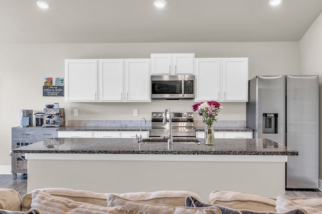 kitchen featuring white cabinetry, a kitchen island with sink, dark stone countertops, and appliances with stainless steel finishes
