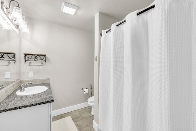 bathroom with toilet, tile patterned flooring, vanity, and baseboards