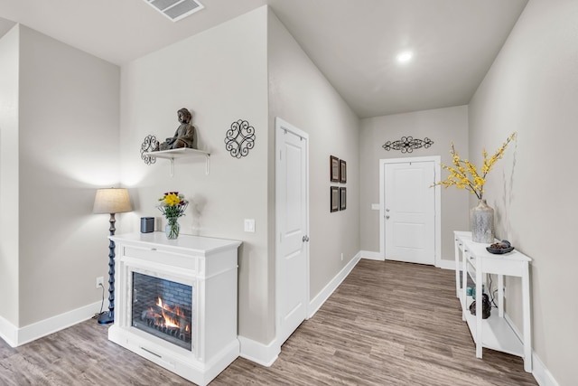 entrance foyer featuring baseboards, a multi sided fireplace, visible vents, and wood finished floors