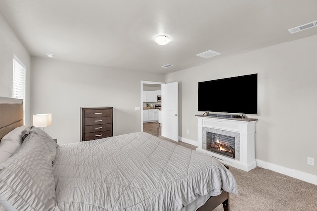 carpeted bedroom featuring visible vents, baseboards, and a warm lit fireplace
