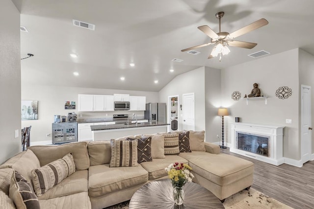living area with vaulted ceiling, visible vents, and baseboards