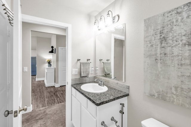 bathroom featuring toilet, baseboards, and vanity
