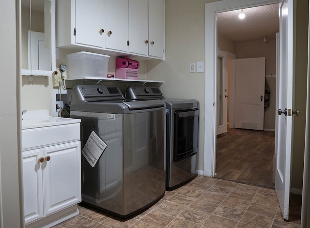 302 County Rd 409, Seminole, TX 79714 - laundry room featuring washing machine and clothes dryer, cabinet space, a textured ceiling, and stone finish flooring