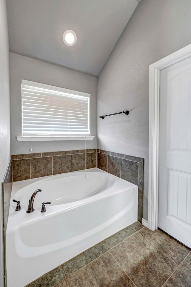 full bathroom with vaulted ceiling and a garden tub