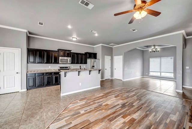 kitchen featuring a breakfast bar area, visible vents, arched walkways, open floor plan, and stainless steel appliances