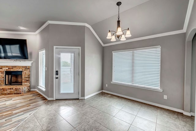 tiled entryway with baseboards, crown molding, a chandelier, and a fireplace