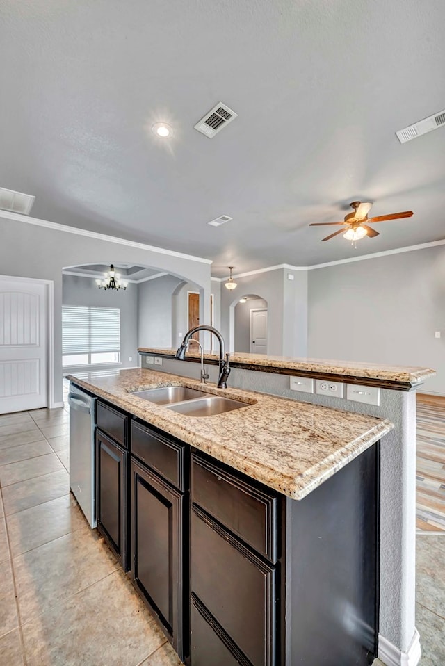 kitchen with a sink, arched walkways, a kitchen island with sink, and visible vents