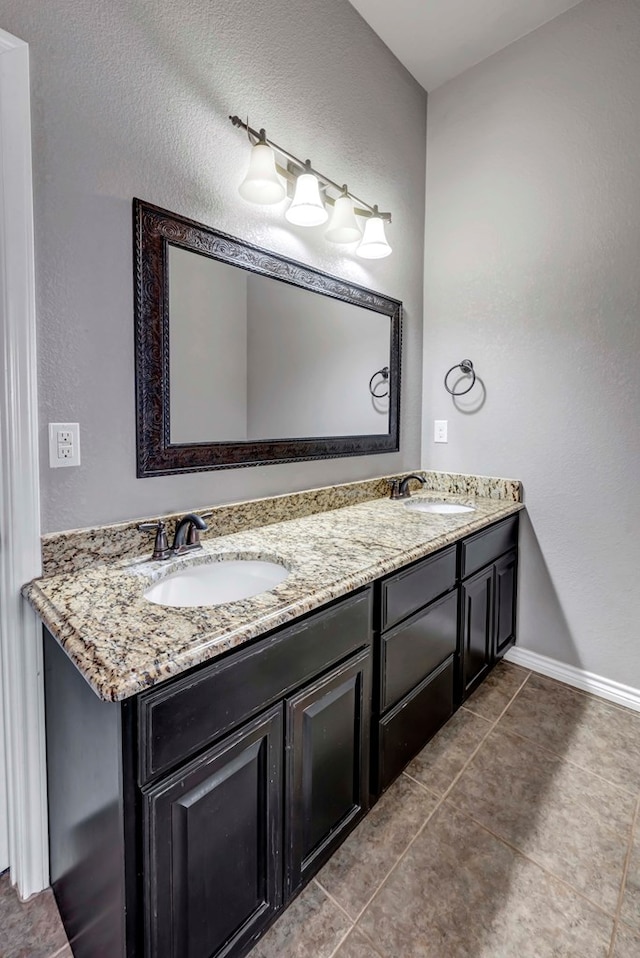 full bathroom with double vanity, baseboards, a sink, and tile patterned flooring