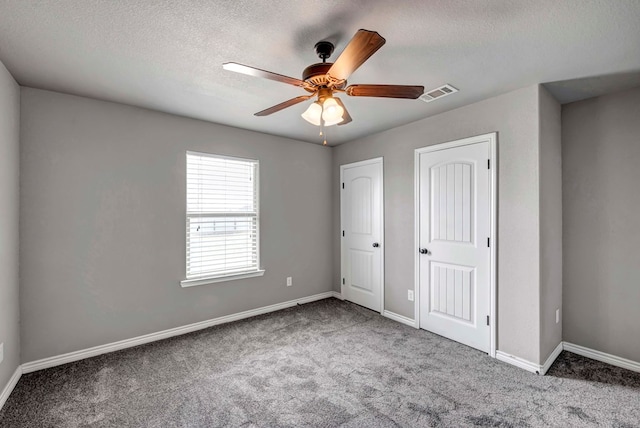 unfurnished bedroom featuring baseboards, carpet flooring, a textured ceiling, and visible vents