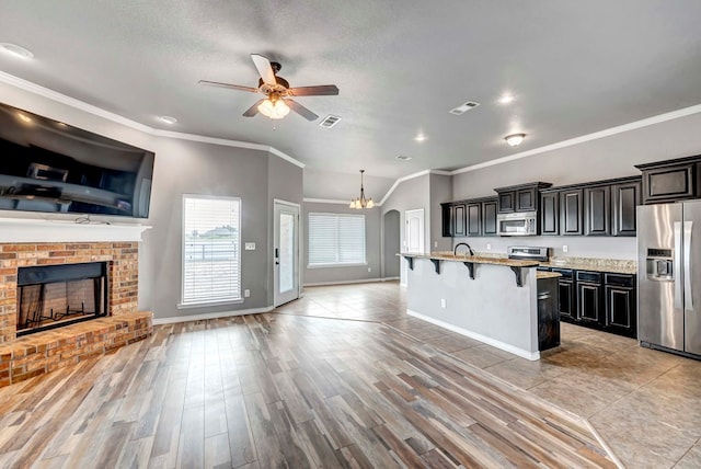 kitchen with stainless steel appliances, open floor plan, a breakfast bar, and ceiling fan with notable chandelier
